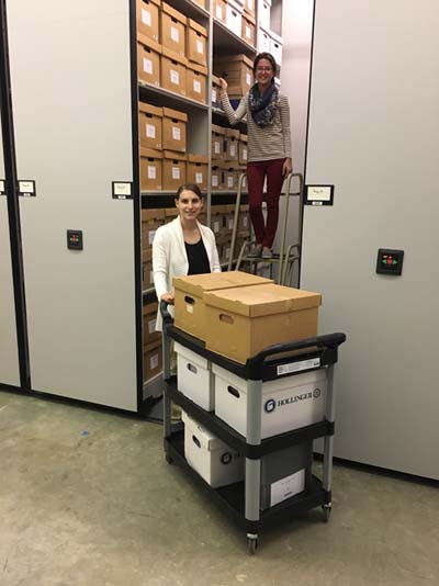 Interns Kahlee and Alex move boxes from Stacks 1 to Stacks 2